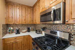 Kitchen with stainless steel appliances, tasteful backsplash, and brown cabinets