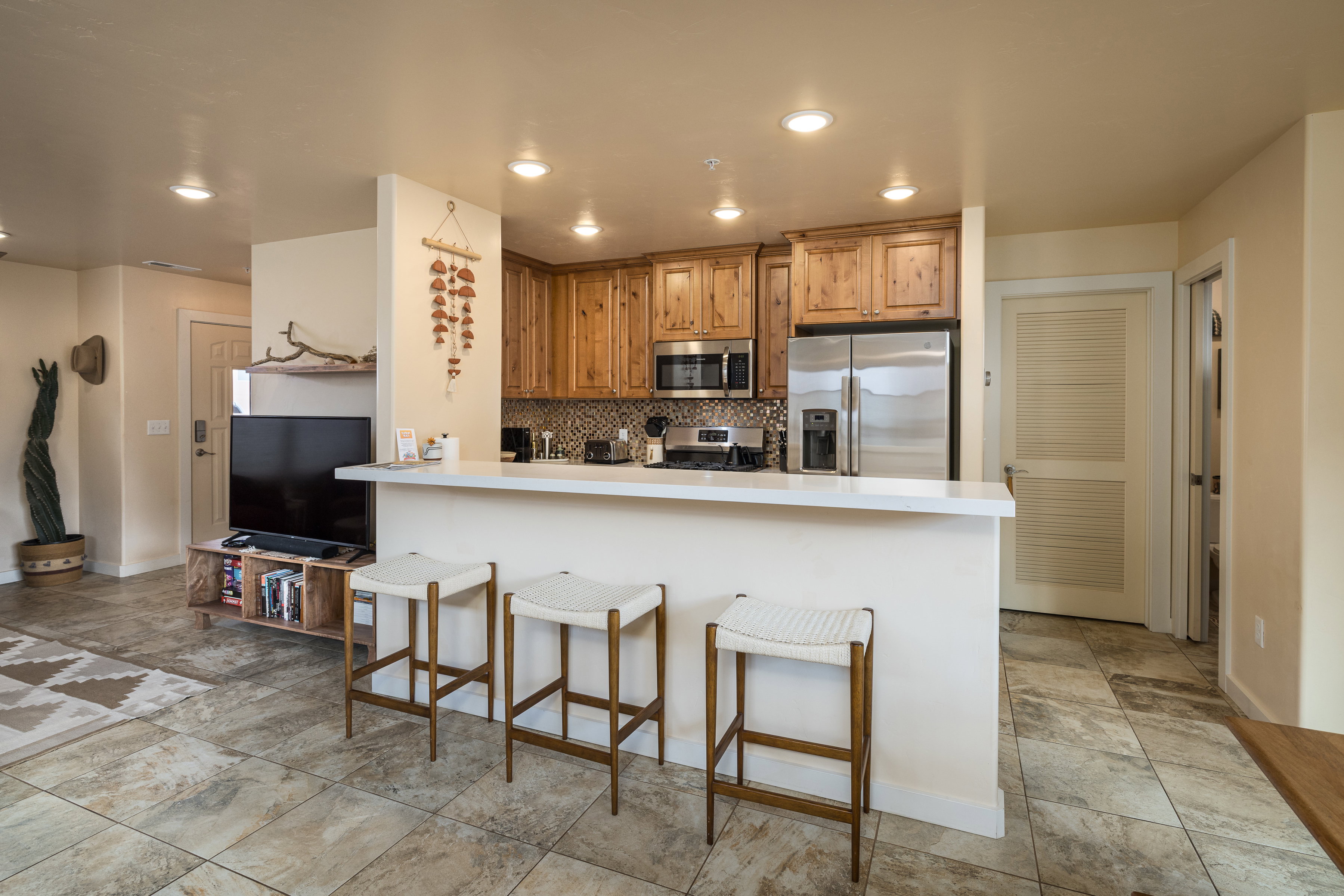 Kitchen with a peninsula, decorative backsplash, stainless steel appliances, a kitchen breakfast bar, and light countertops