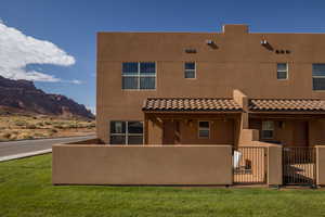 Back of house featuring a gate, stucco siding, a mountain view, and a tile roof