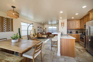 Kitchen with light countertops, decorative backsplash, open floor plan, a kitchen breakfast bar, and appliances with stainless steel finishes