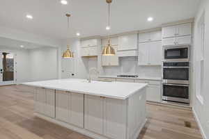 Kitchen featuring tasteful backsplash, recessed lighting, hanging light fixtures, white cabinets, and light wood-style floors