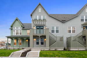 View of front of property with stairway, roof with shingles, and a balcony