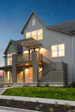 Back of property featuring stucco siding, stairway, a pergola, and a yard