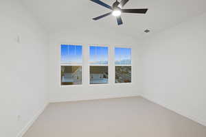 Unfurnished room featuring light carpet, lofted ceiling, and ceiling fan