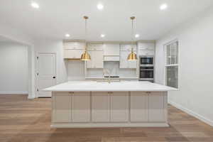 Kitchen featuring decorative backsplash, light wood finished floors, appliances with stainless steel finishes, recessed lighting, and pendant lighting