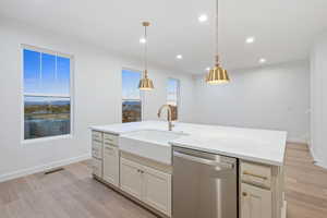 Kitchen featuring stainless steel dishwasher, light wood-type flooring, decorative light fixtures, light stone counters, and recessed lighting