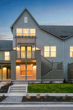 View of front of property with a balcony, stairway, and roof with shingles