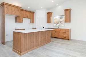 Kitchen with recessed lighting, a center island, light wood-style floors, and light stone countertops