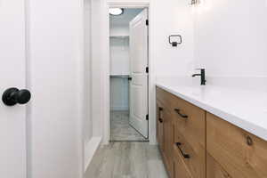Full bath featuring a walk in closet, vanity, and light wood finished floors