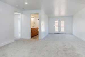 Unfurnished room featuring light carpet and baseboards