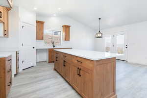 Kitchen featuring vaulted ceiling, a kitchen island, light wood-type flooring, decorative light fixtures, and recessed lighting