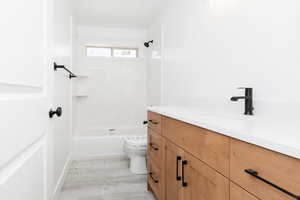 Full bath with vanity, bathtub / shower combination, and light wood finished floors