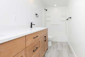 Bathroom featuring double vanity, bathing tub / shower combination, light wood-type flooring, and recessed lighting