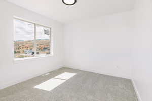 Carpeted spare room featuring baseboards