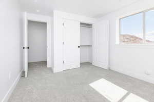 Unfurnished bedroom with light colored carpet and a closet