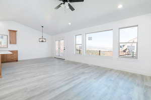 Unfurnished living room featuring light wood-type flooring, vaulted ceiling, a ceiling fan, and recessed lighting