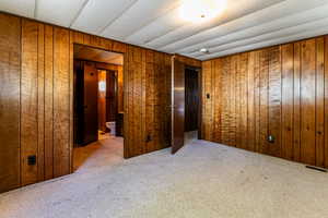 Unfurnished bedroom with carpet and wooden walls