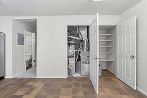 Utility room with gas water heater, electric panel, and heating unit