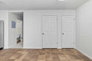 Unfurnished bedroom featuring stainless steel refrigerator, electric panel, and a textured ceiling