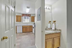 Full bath featuring a textured ceiling, two vanities, light tile patterned floors, and electric panel