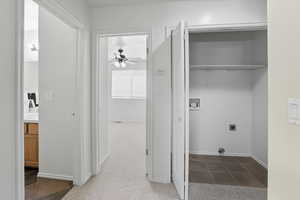 Laundry room with dark tile patterned floors, dark carpet, washer hookup, a ceiling fan, and electric dryer hookup