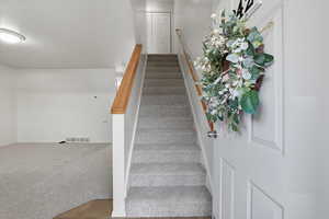 Stairs featuring carpet floors and a textured ceiling