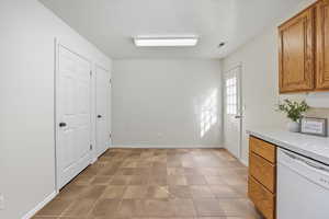 Kitchen featuring dishwasher, brown cabinetry, light countertops, and a textured ceiling
