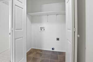 Laundry room with hookup for a washing machine, hookup for an electric dryer, and dark tile patterned flooring