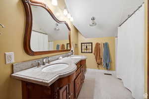 Bathroom featuring double vanity, tile patterned flooring, lofted ceiling, and curtained shower