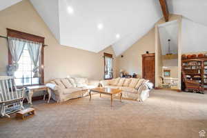 Living area with carpet floors, recessed lighting, high vaulted ceiling, and beam ceiling