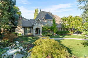 View of front facade with stone siding, a front lawn, and stucco siding