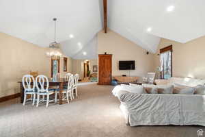 Carpeted living area with beamed ceiling, high vaulted ceiling, recessed lighting, a chandelier, and arched walkways