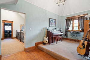 Home office featuring wood finished floors, plenty of natural light, high vaulted ceiling, a chandelier, and carpet floors