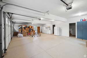 Garage with freestanding refrigerator, washing machine and dryer, and a garage door opener