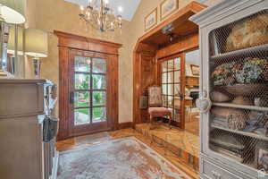 Doorway featuring a chandelier and vaulted ceiling