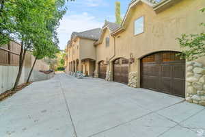 Exterior space featuring driveway, stone siding, stucco siding, and a garage