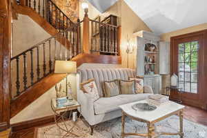 Living room with vaulted ceiling, a textured wall, and stairway