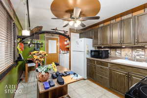 Kitchen with washing machine and dryer, black appliances, light countertops, ceiling fan, and backsplash