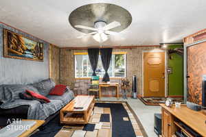 Living room featuring a textured ceiling, light colored carpet, ceiling fan, and crown molding