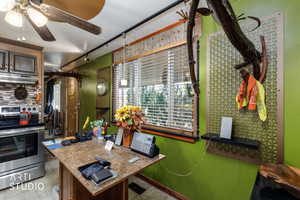 Kitchen with electric stove, under cabinet range hood, rail lighting, ceiling fan, and tile patterned flooring