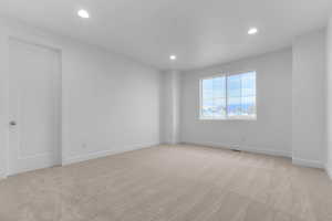 Empty room with light carpet and recessed lighting