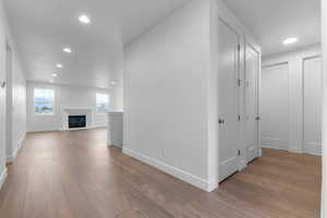 Unfurnished living room featuring recessed lighting, light wood-style floors, and a glass covered fireplace