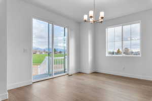 Unfurnished room featuring plenty of natural light, a chandelier, and light wood-style flooring