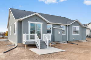 Rear view of property featuring a patio area, stucco siding, and a shingled roof