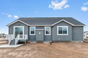 Back of house with stucco siding and a shingled roof