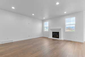 Unfurnished living room featuring recessed lighting, light wood-type flooring, and a glass covered fireplace