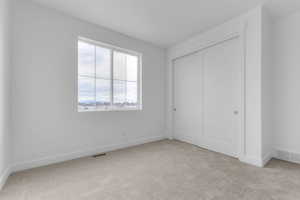 Unfurnished bedroom featuring light carpet and a closet