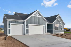 Modern farmhouse style home featuring an attached garage, board and batten siding, driveway, and a shingled roof