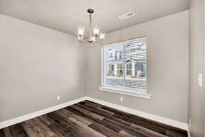 Unfurnished dining area featuring a chandelier and dark wood finished floors