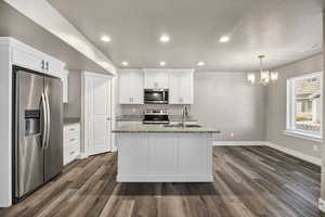 Kitchen with stainless steel appliances, recessed lighting, light stone counters, white cabinetry, and dark wood-style flooring